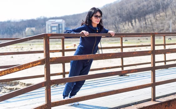 45 y.o. Russian woman doing 
push ups on a wooden bridge at beach