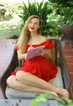 Beautiful blonde woman artist and illustrator thinking about idea of a drawing, sitting on a couch