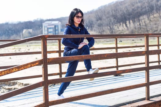 45 y.o. Russian woman stretching  on a wooden bridge at beach
