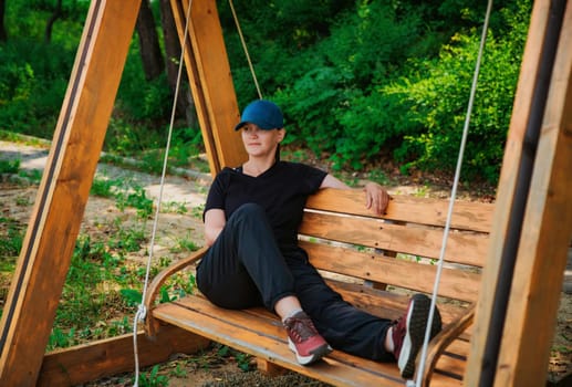 Young russian woman it sport outwear resting on swing after making exercises