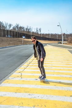 Young man riding a skateboard on a pedestrian cross road