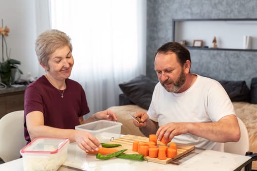 Mature russian husband and wife cooking pilaf together in the kitchen at homeMature russian husband and wife cooking pilaf together in the kitchen at home