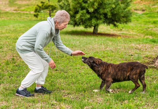 Mature woman playing with her dog outdoors