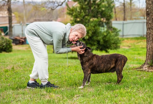 Mature woman playing with her dog outdoors
