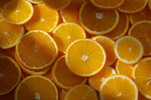 A colorful arrangement of orange slices reveals their juicy texture under warm sunlight, showcasing natural beauty.