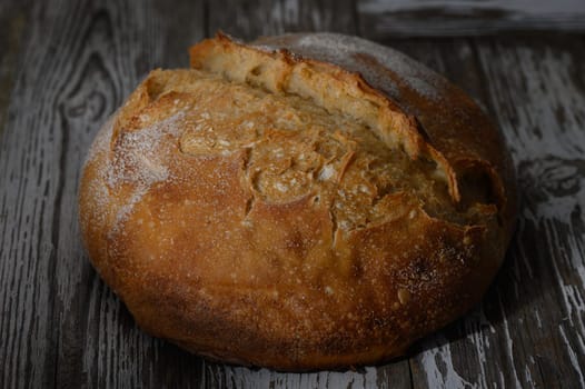 Golden crusted artisan bread sits invitingly on a rustic wooden surface, ready to be enjoyed fresh from the oven.