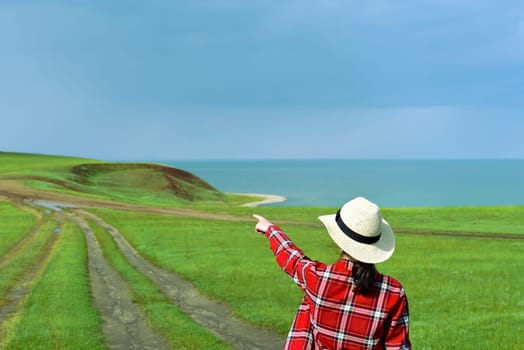 Young girl in red shirt pointing her finger to the path of Cape Kharantsy