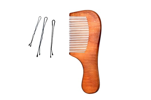 Wooden comb and three black invisible hairpins isolated on white background.