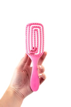 Female hand holding aroma hair comb for massage of head isolated on white background.