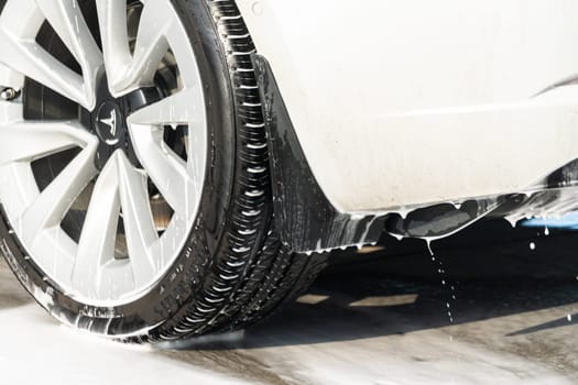 Denver, Colorado, USA-September 1, 2023-Efficiently cleaning an electric car in the comfort of a suburban driveway, combining eco-consciousness with practicality.