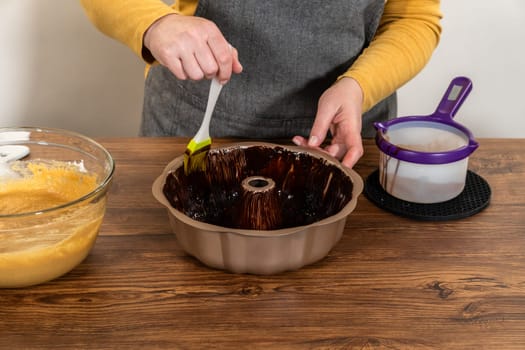 Carefully greasing a bundt cake pan in preparation for baking a delicious gingerbread bundt cake with caramel frosting.