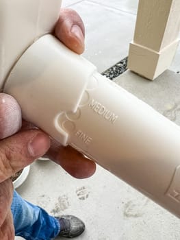 Castle Rock, Colorado, USA-April 26, 2023-A close-up of a person holding a broken wall texturing tool The plastic device appears damaged possibly from improper use or storage The background shows a wet driveway and a parked white vehicle indicating rainy weather