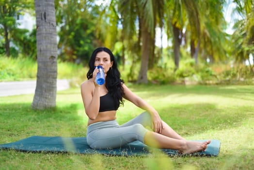Ukrainian beautiful woman drinking water after doing yoga on the map outside