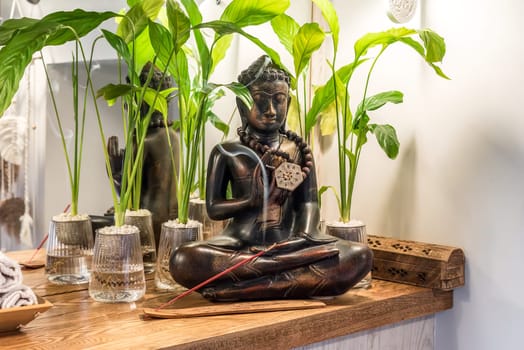 Spathiphyllum cochlearispathum commonly called peace lily growing in water in glass, with buddha