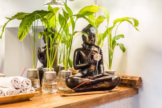 Spathiphyllum cochlearispathum commonly called peace lily growing in water in glass, with buddha