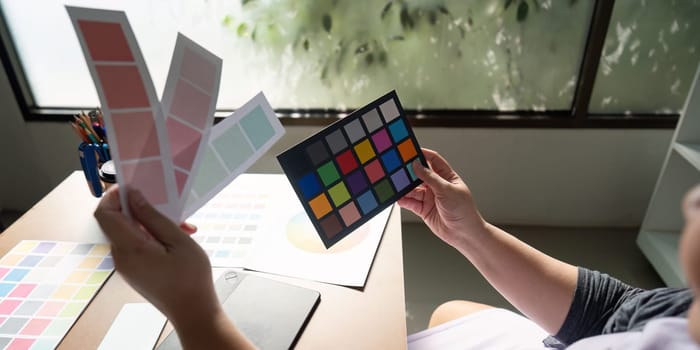 A graphic designer examining color palettes and samples, actively engaged in the design process at a bright and inspiring workspace.
