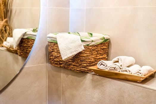 wooden wicker basket with towels on wooden shelf for bathroom