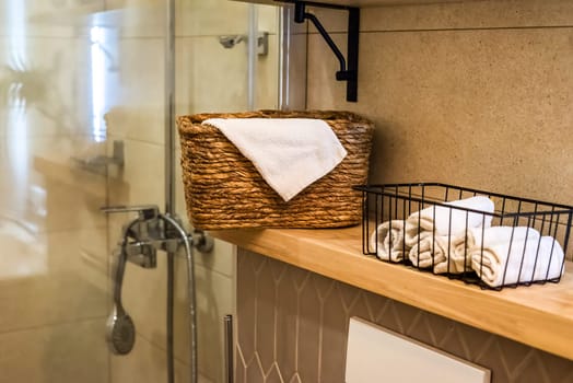 wooden wicker basket with towels on wooden shelf for bathroom