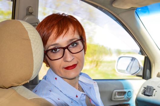 Business woman with glasses sitting on the seat of taxi car and looking at the camera. way to office