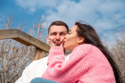Funny portrait of young married russian couple, woman kissing her husband but he making a funny face