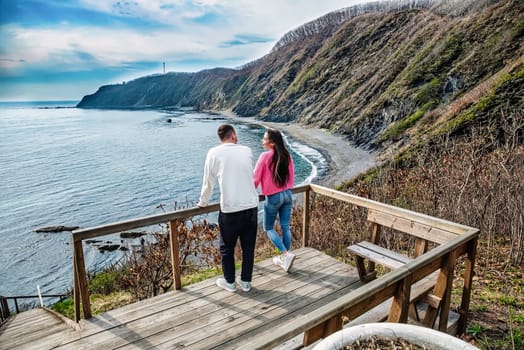 married couple standing together on the stairs and looking at sea view