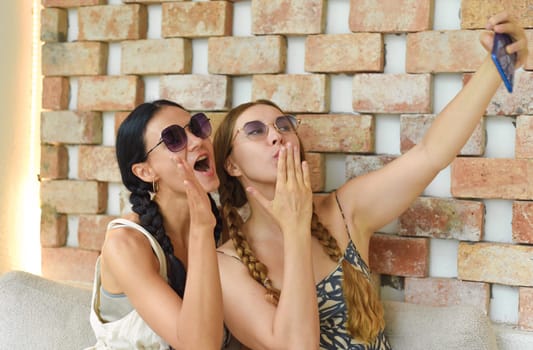 Ukrainian woman (brunette) and Russian woman (blonde) portrait together with braids posing and taking a selfie