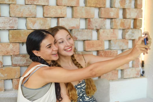Ukrainian woman (brunette) and Russian woman (blonde) portrait together with braids posing and taking a selfie