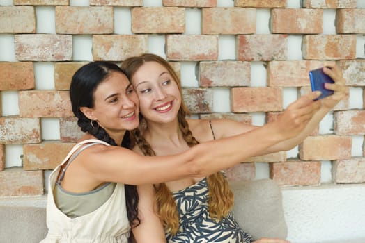 Ukrainian woman (brunette) and Russian woman (blonde) portrait together with braids posing and taking a selfie