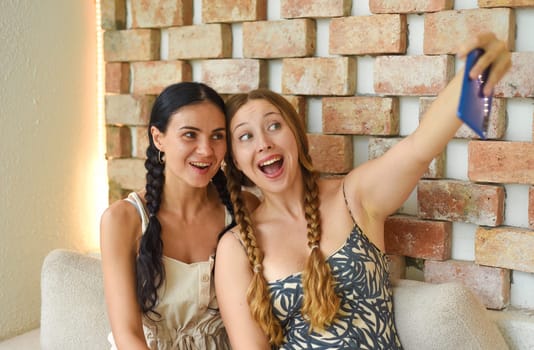 Ukrainian woman (brunette) and Russian woman (blonde) portrait together with braids posing and taking a selfie