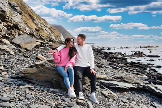 Young russian couple sitting on the stone near Japanese sea on a sunny day
