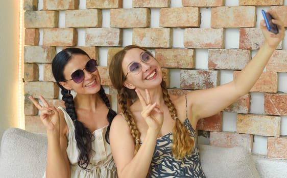 Ukrainian woman (brunette) and Russian woman (blonde) portrait together with braids posing and taking a selfie