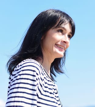45 years old Russian woman laughing and standing against blue sky