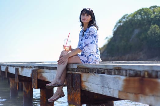 45 years old Russian woman drinking lemonade and sitting on pier
