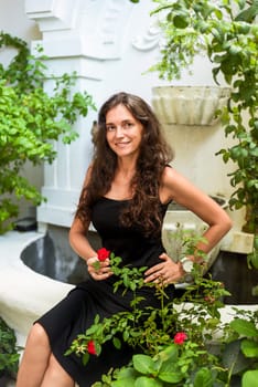 Portrait of 39 years old russian woman close up without make up sitting with red roses in black dress