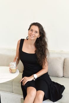 Successful 40 year old sitting in a cafe with glass of ice coffee and looking left