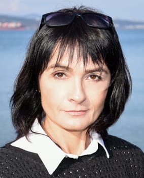 Young brunette woman 45 y.o. with short hair looking at the camera. Close up portrait