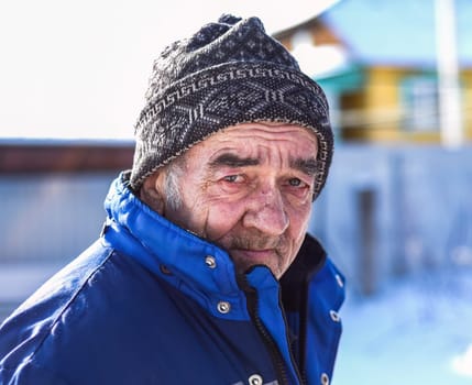 Portrait of old Russian man looking sadly in the camera on winter background