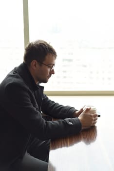Upset depressive russian man looking thoughtfully to the side. paper cup of coffee in hands. sadness and despair concept