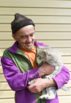 Old Russian man holding a cat and laughing