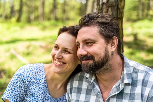Portrait of young married couple sitting in the forest on a sunny day