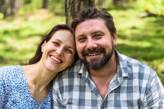 Portrait of young married couple sitting in the forest on a sunny day