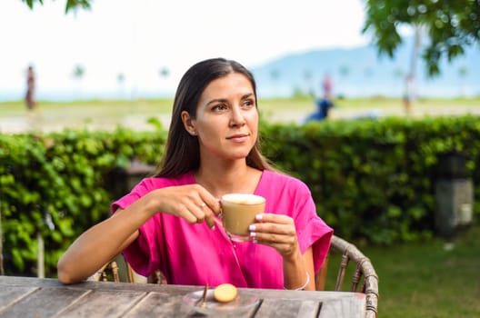 Portrait of smiling russian woman drinking hot capuccino and looking left