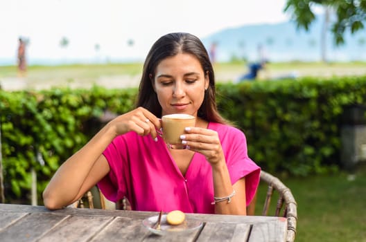Portrait of smiling russian woman drinking hot capuccino and looking left