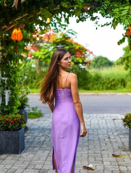 Portrait of russian young woman with long hair against green leaves