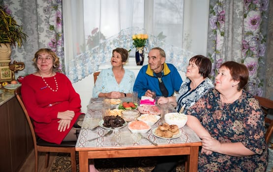 Family and senior friends eating together and watching tv show together at home
