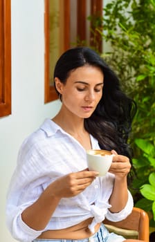 Portrait of smiling ukrainian woman drinking hot capuccino and looking at camera