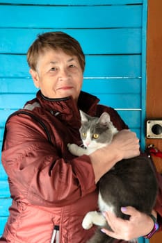 Old Russian woman holding her cat and smiling