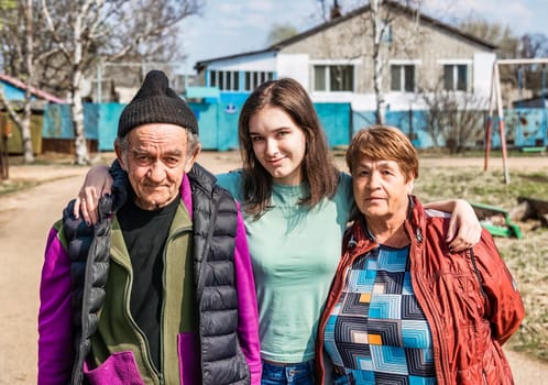 Portrait of 75 years old grandparents and their granddaughter in russian village together
