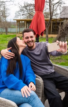 Young married couple making a selfie and laughing on the backyard of their house