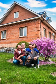 Portrait of happy family together hugging near their big house.